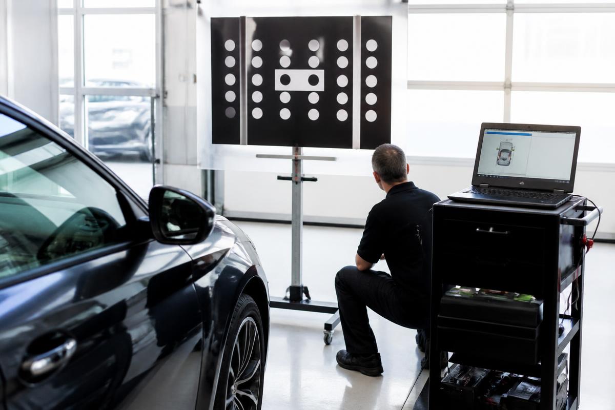 ADAS windshield camera calibration with a target board and laptop in a service bay