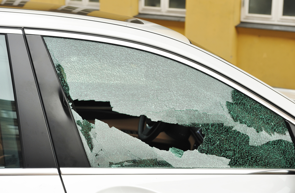 Shattered front door window glass on a white car