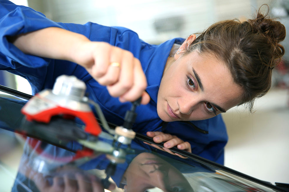 Technician using a resin bridge tool to repair a crack in a windshield